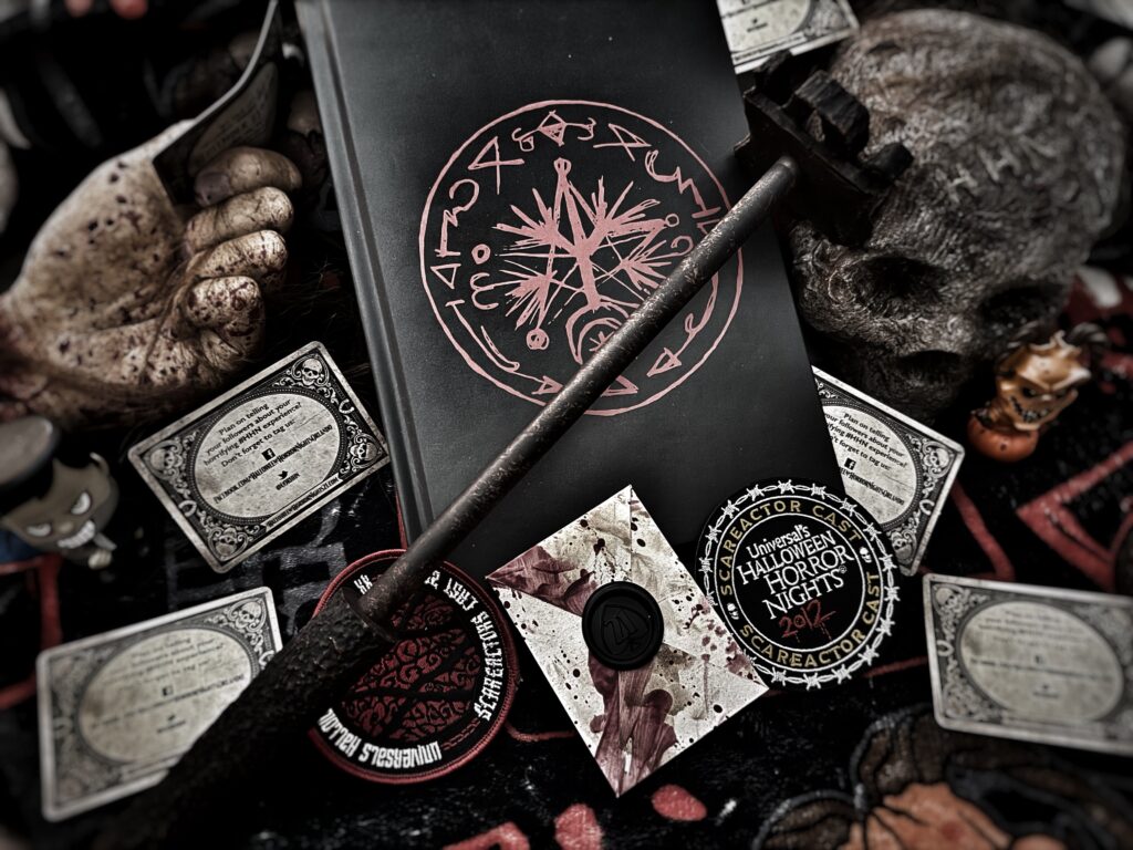 Our friends at HNNightmares made this creepy collage of a horror-themed flat lay featuring Horrors Untold with red occult symbols, a bloody envelope sealed with wax, Halloween Horror Nights memorabilia, a skull, and a rusted mallet, creating a sinister and mysterious atmosphere.
